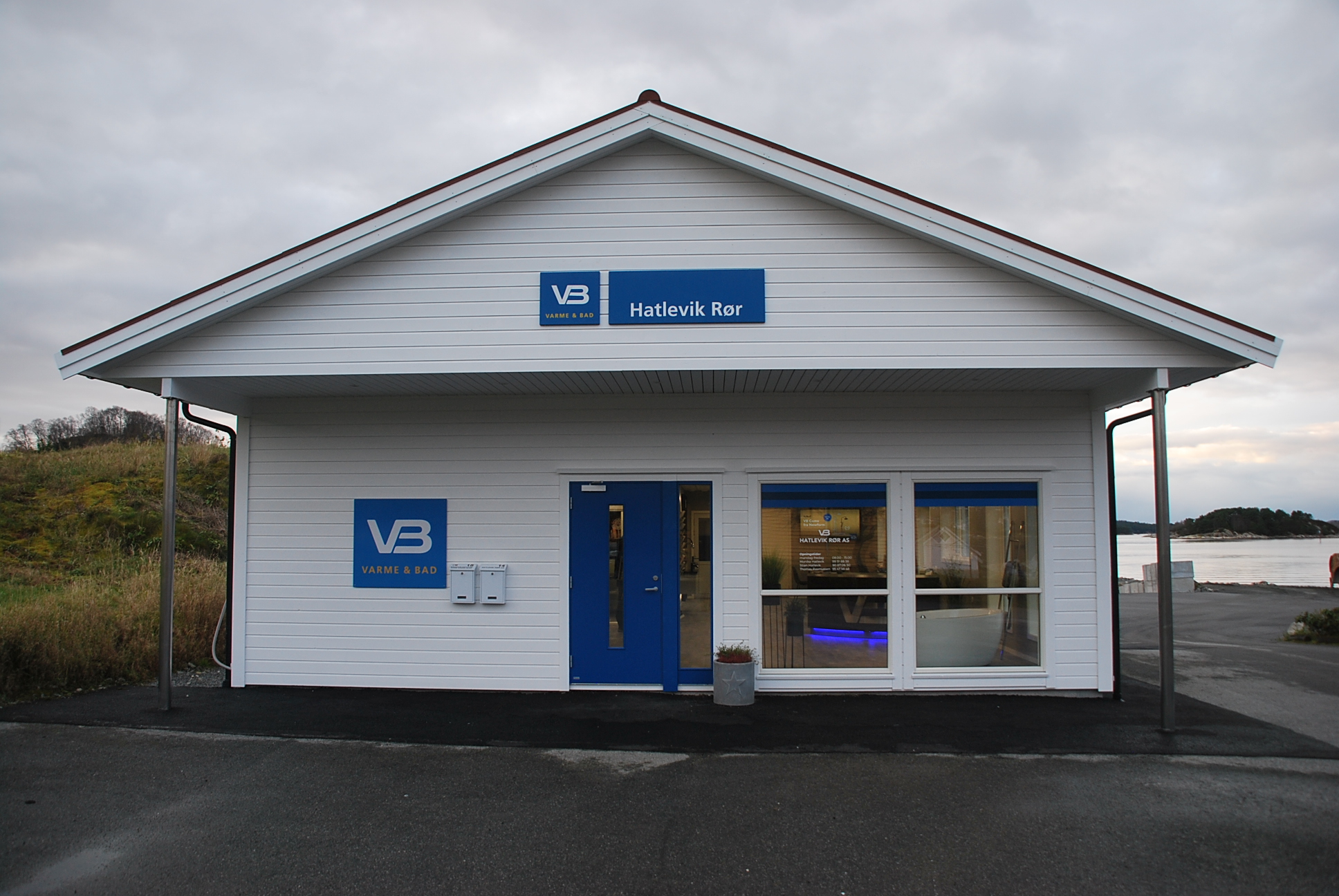 Fasadebilde av inngangspartiet til Hatlevik Rør, preget av hvit kledning, blå detaljer og VB-logo.